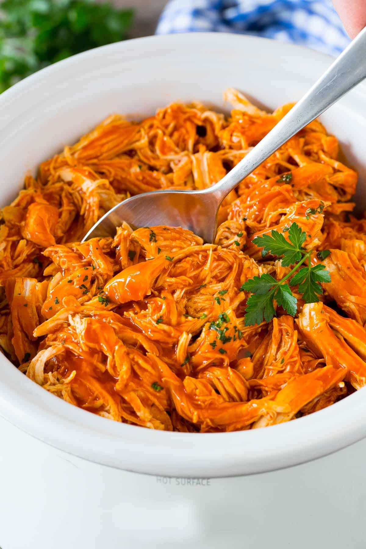 Crock pot buffalo chicken with a serving spoon in it.