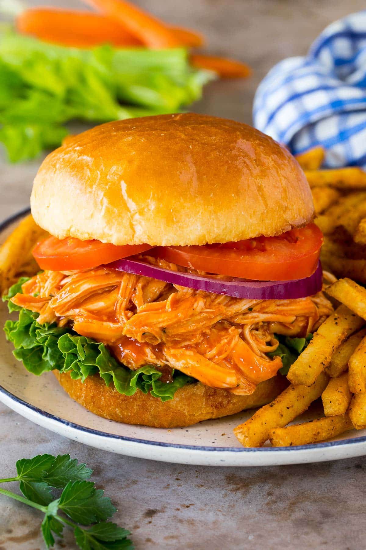 A sandwich made with crock pot buffalo chicken, served with french fries.