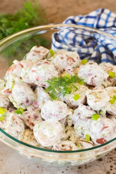 A serving bowl of dill potato salad garnished with herbs.