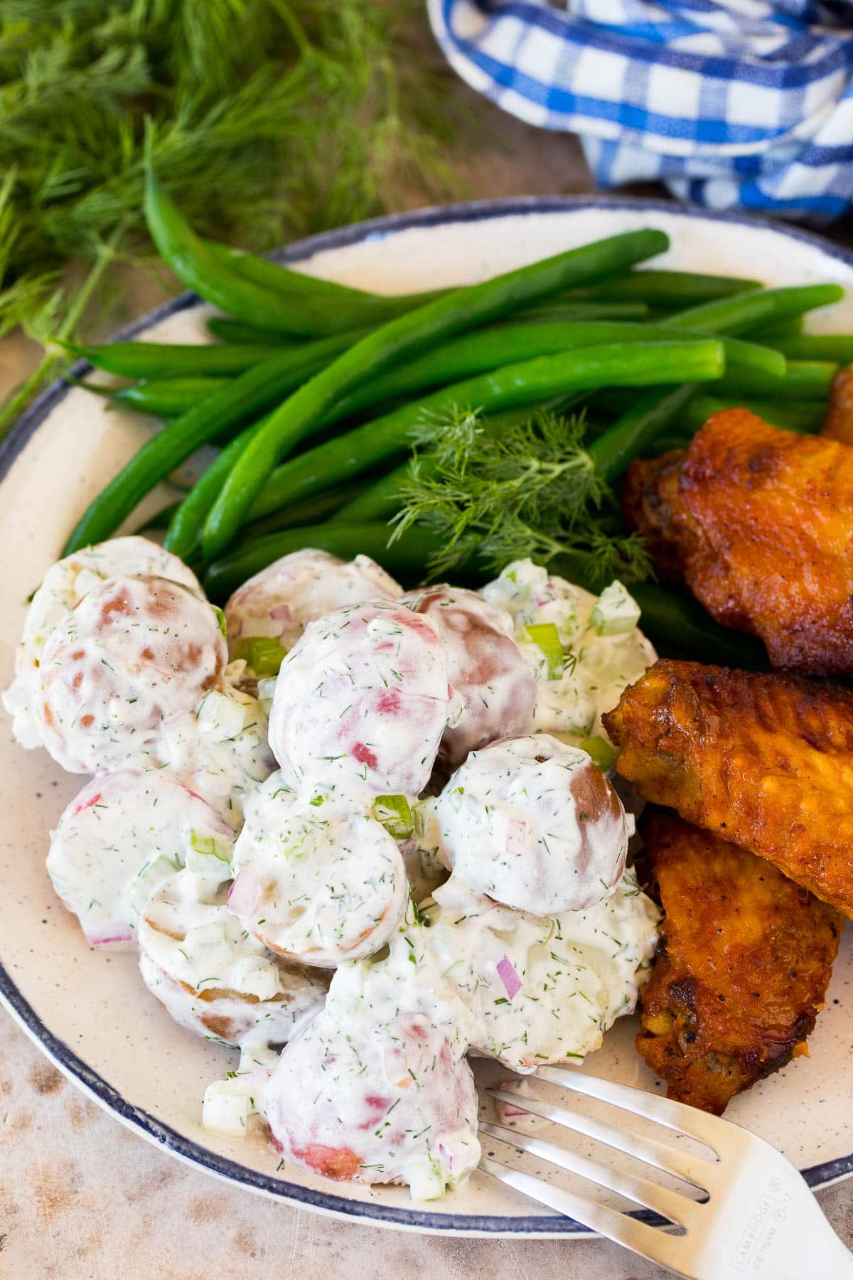 Dill potato salad served with chicken wings and green beans.