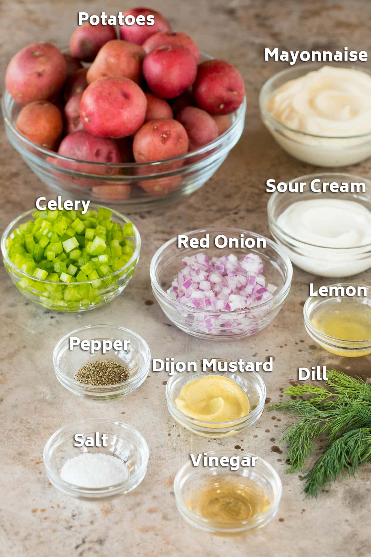 Bowls of ingredients including potatoes, vegetables, mayonnaise and seasonings.