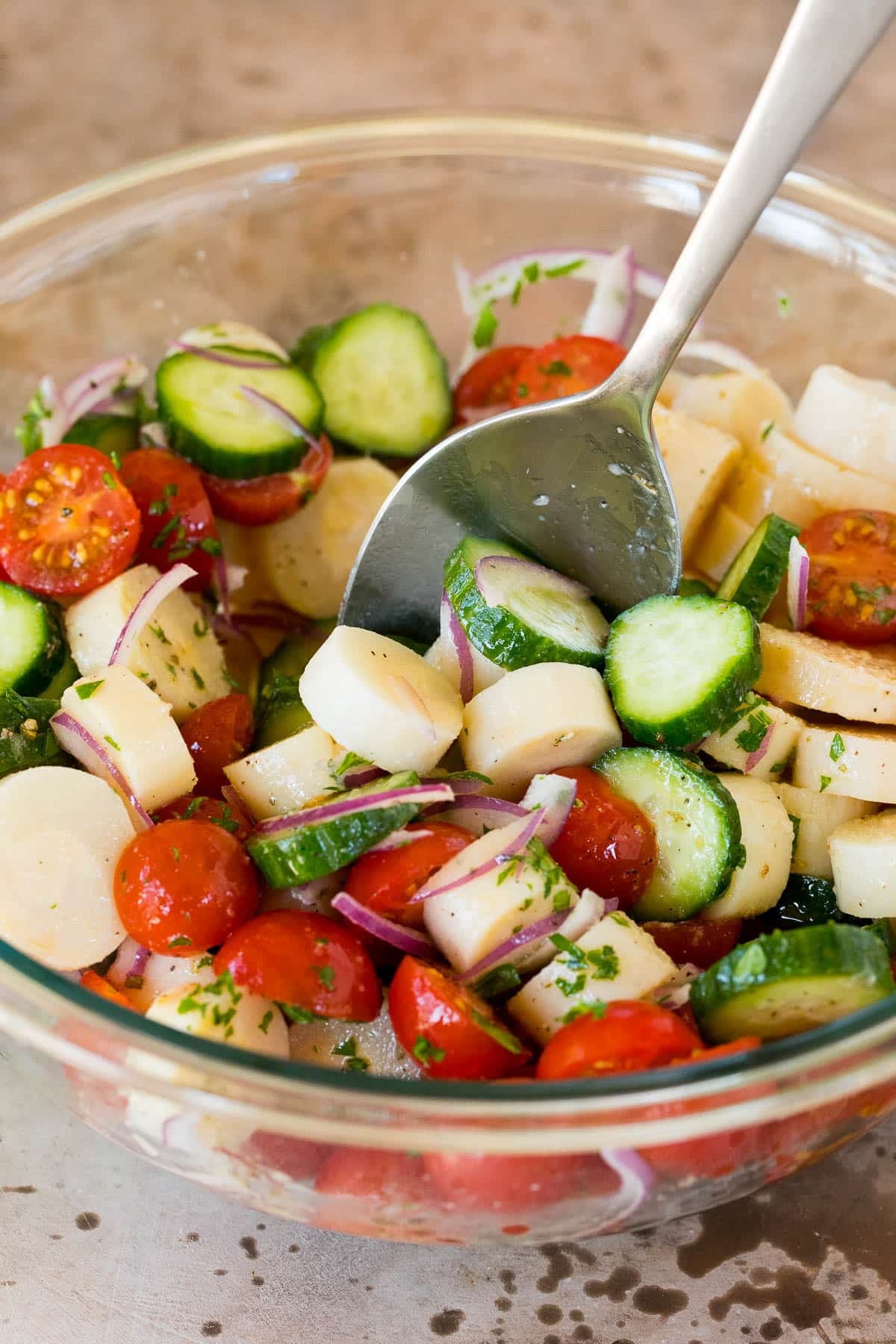 A spoon stirring together a salad.