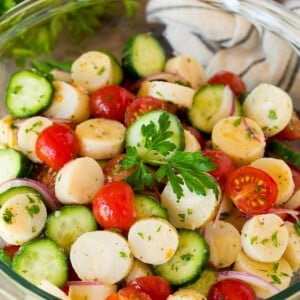 A serving bowl of hearts of palm salad garnished with a sprig of parsley.