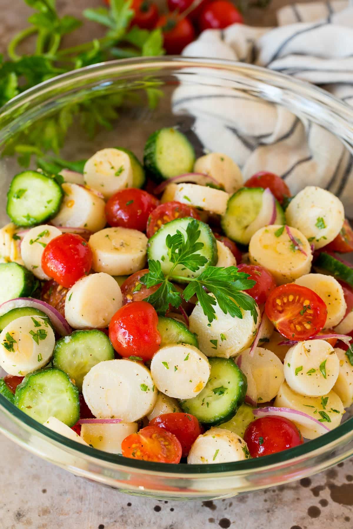 A serving bowl of hearts of palm salad garnished with a sprig of parsley.