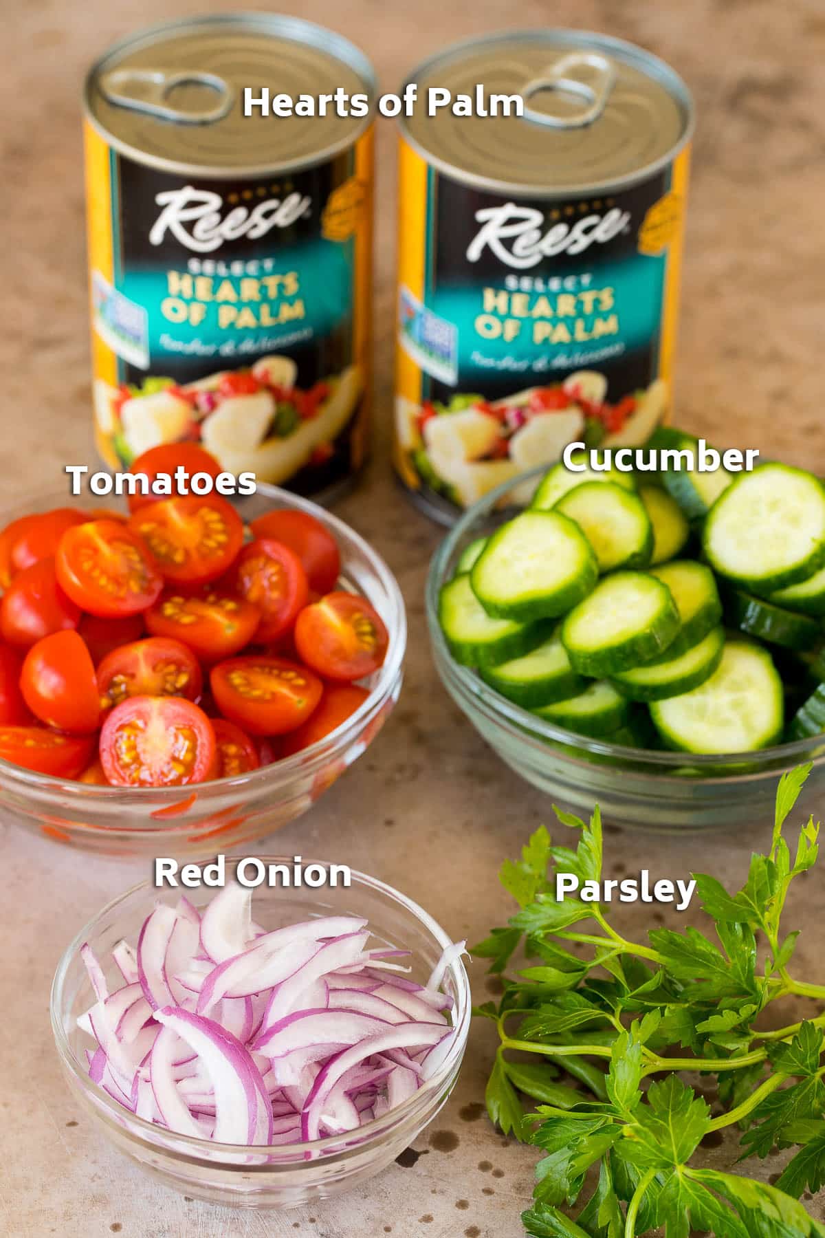 Cans of hearts of palm and bowls of sliced vegetables.