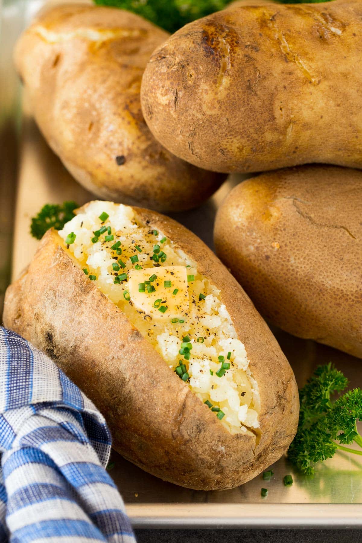 A tray of Instant Pot baked potatoes topped with butter and chives.