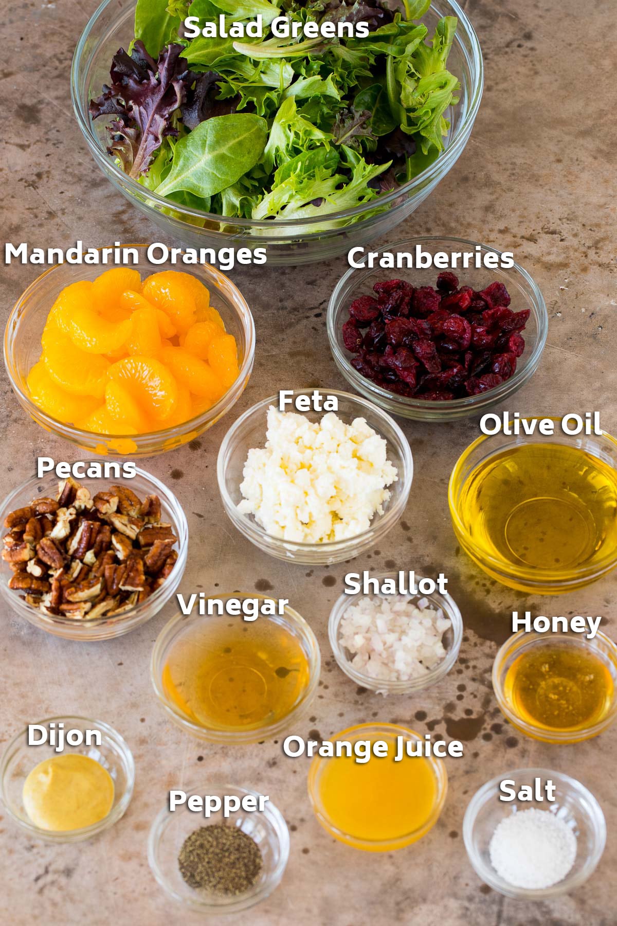 Bowls of ingredients including fruit, nuts, cheese, olive oil, vinegar and seasonings.
