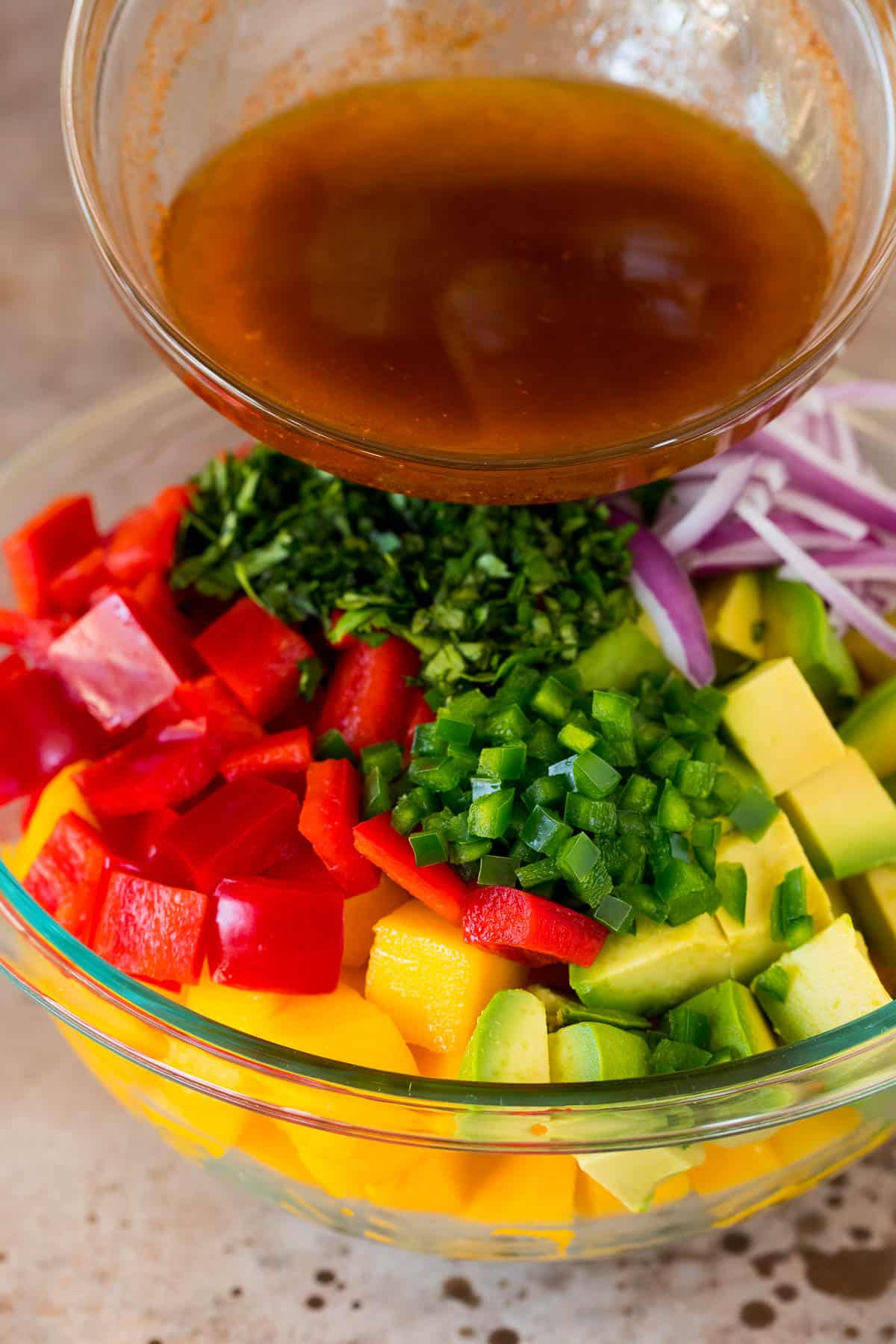 Dressing being poured over mango and vegetables.