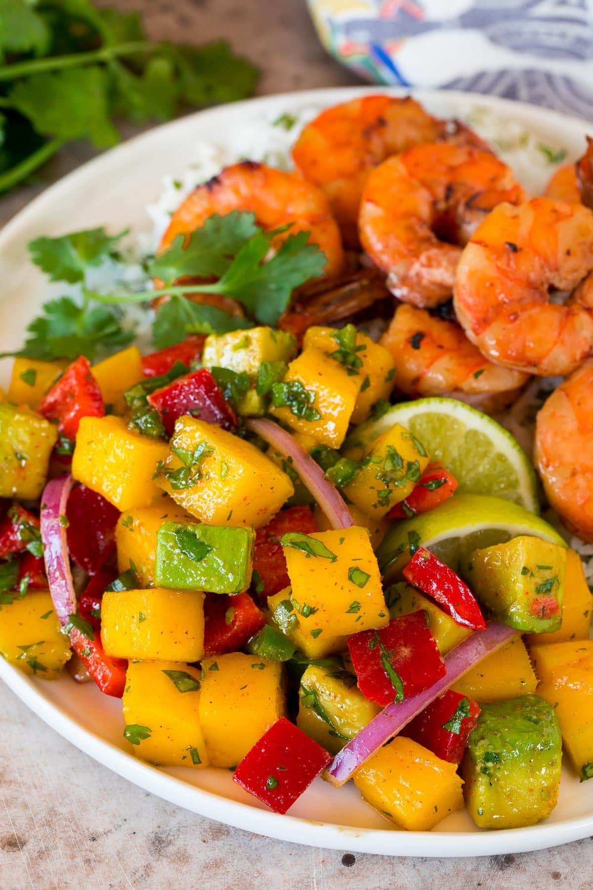 Mango salad on a plate with shrimp and rice.