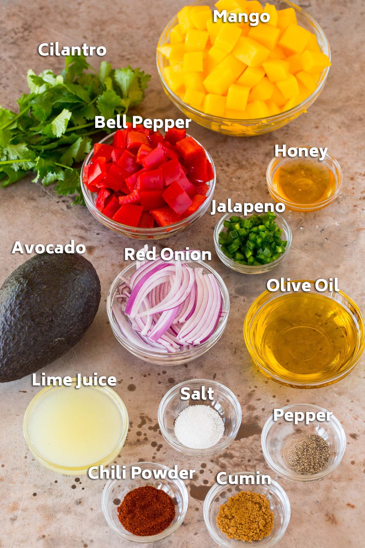 Bowls of ingredients including mango, vegetables, lime juice, olive oil and seasonings.