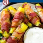 A plate of bacon wrapped pickles which are pickle spears wrapped in smoky bacon, then baked to crispy perfection.
