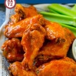 A plate of baked buffalo wings which are ultra crispy chicken wings tossed in a classic spicy sauce.