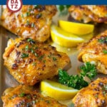 A sheet pan with baked chicken thighs which are coated in olive oil, garlic and herbs, then oven roasted until tender and golden brown.
