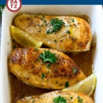 A baking dish with baked lemon chicken coated in a butter and herb sauce and roasted to perfection.