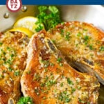 A pan with baked pork chops that are coated in garlic and herb butter then oven roasted to golden brown perfection.