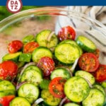 A bowl of cucumber tomato salad which is full of fresh sliced cucumbers, cherry tomatoes, red onion and green peppers, all tossed in an herb dressing.