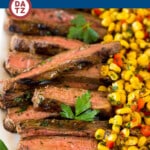 A plate of grilled flank steak which is coated in a flavorful marinade, then cooked on a grill until perfectly tender and juicy.