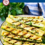 A plate of grilled zucchini which is zucchini is bathed in a flavorful garlic and herb marinade, then cooked to perfection on the grill.