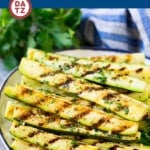 A plate of grilled zucchini which is zucchini is bathed in a flavorful garlic and herb marinade, then cooked to perfection on the grill.
