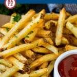 A plate of homemade french fries which are potatoes that are cut into sticks and deep fried until golden brown, then sprinkled with seasonings.