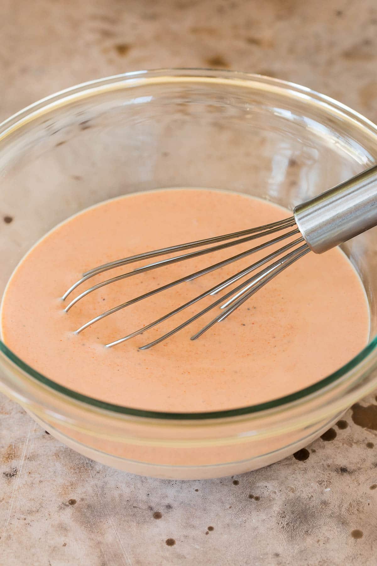 A bowl of sauce with a whisk in it.