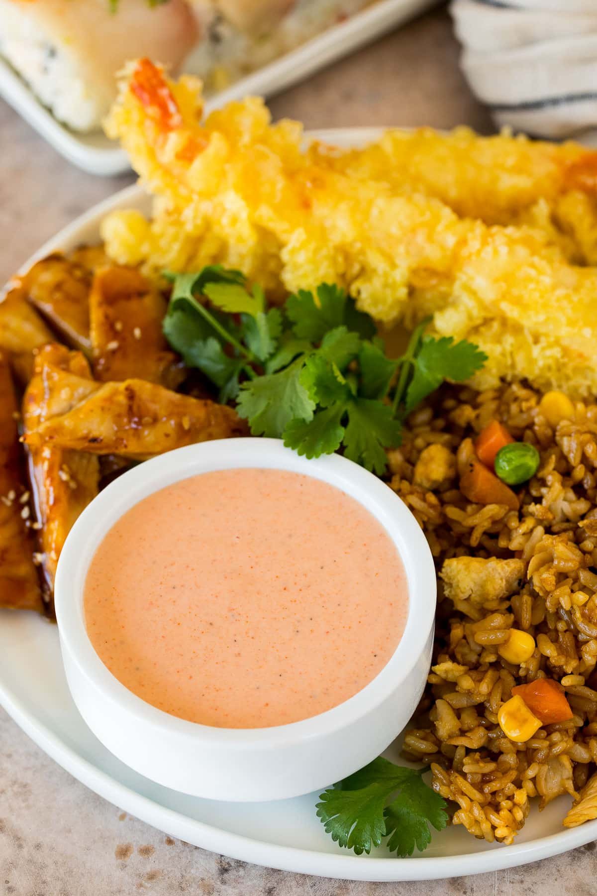 A bowl of yum yum sauce served with fried rice, chicken and tempura shrimp.