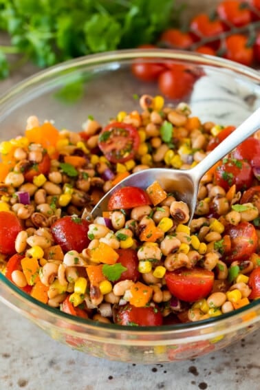 A spoon in a bowl serving up black eyed pea salad.