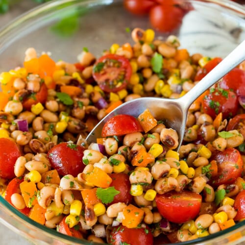 A spoon in a bowl serving up black eyed pea salad.