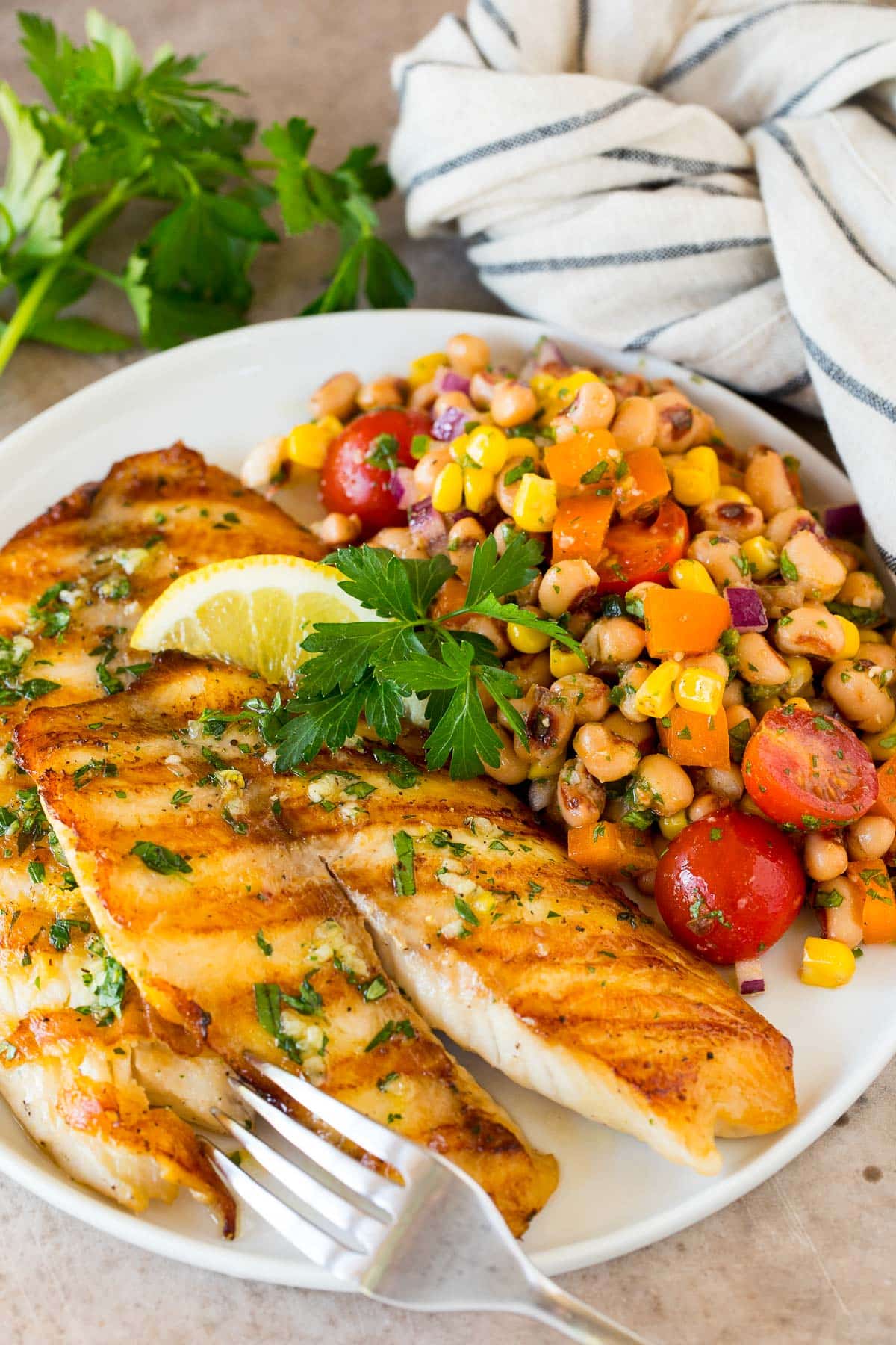 A plate of black eyed pea salad served with grilled fish.