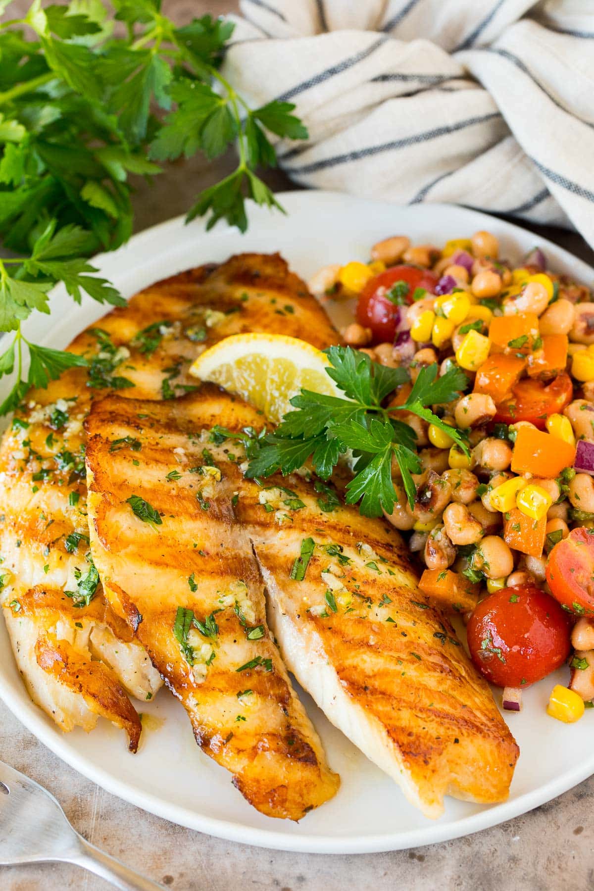 Grilled tilapia on a plate with bean salad.
