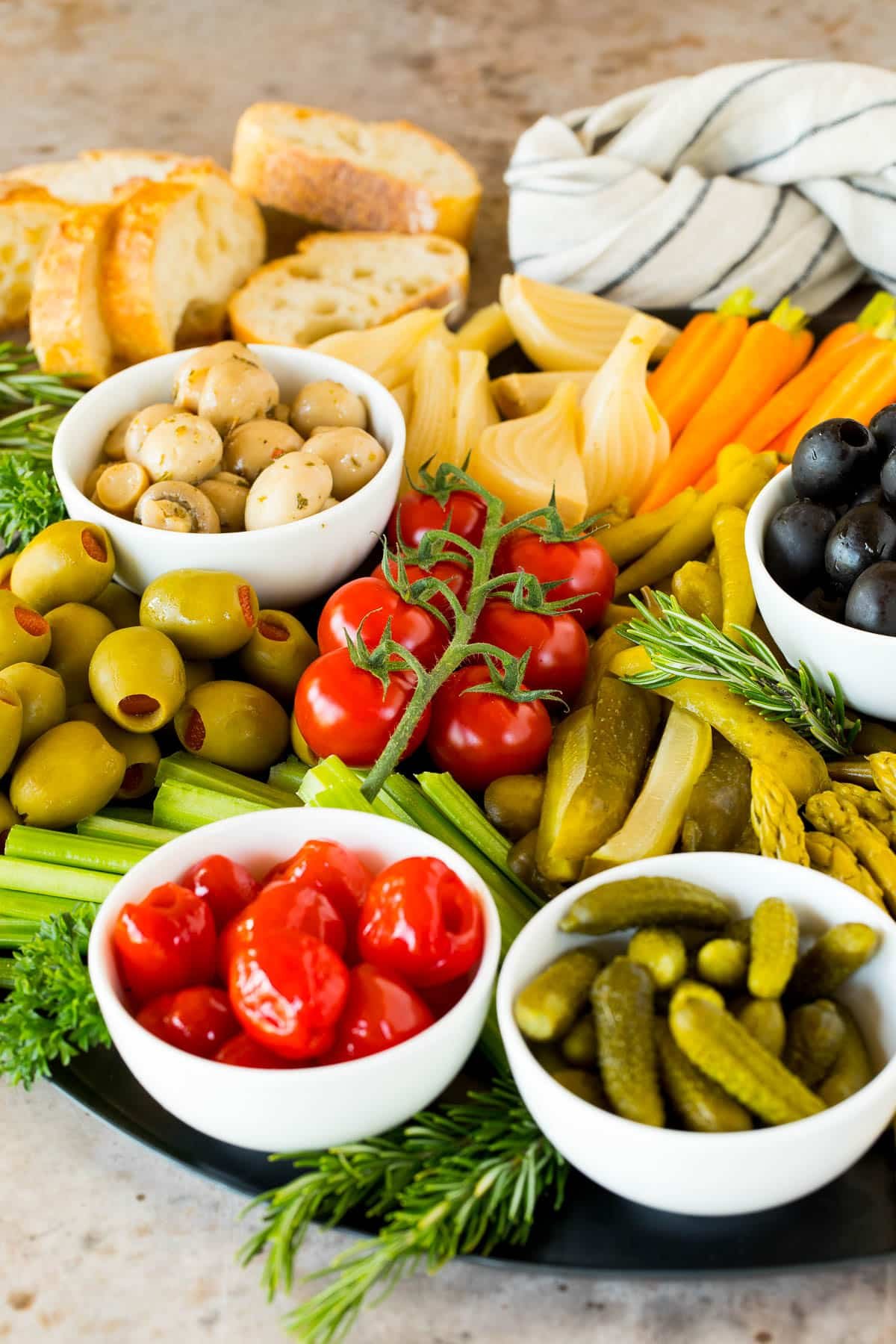 A close up of a relish tray featuring pickles, olives and peppers.