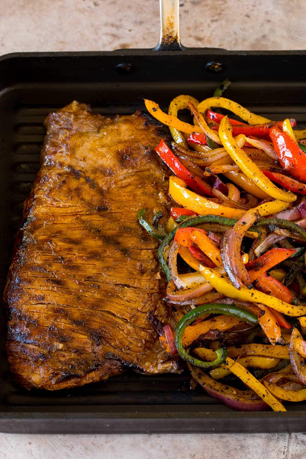 Flank steak and veggies cooked in a grill pan.