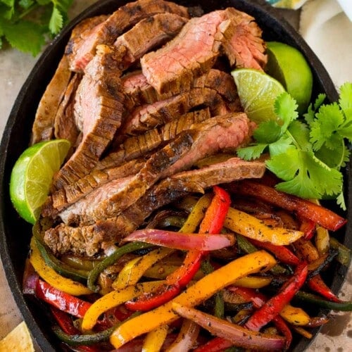 Steak fajita marinade coated meat and peppers in a cast iron pan.