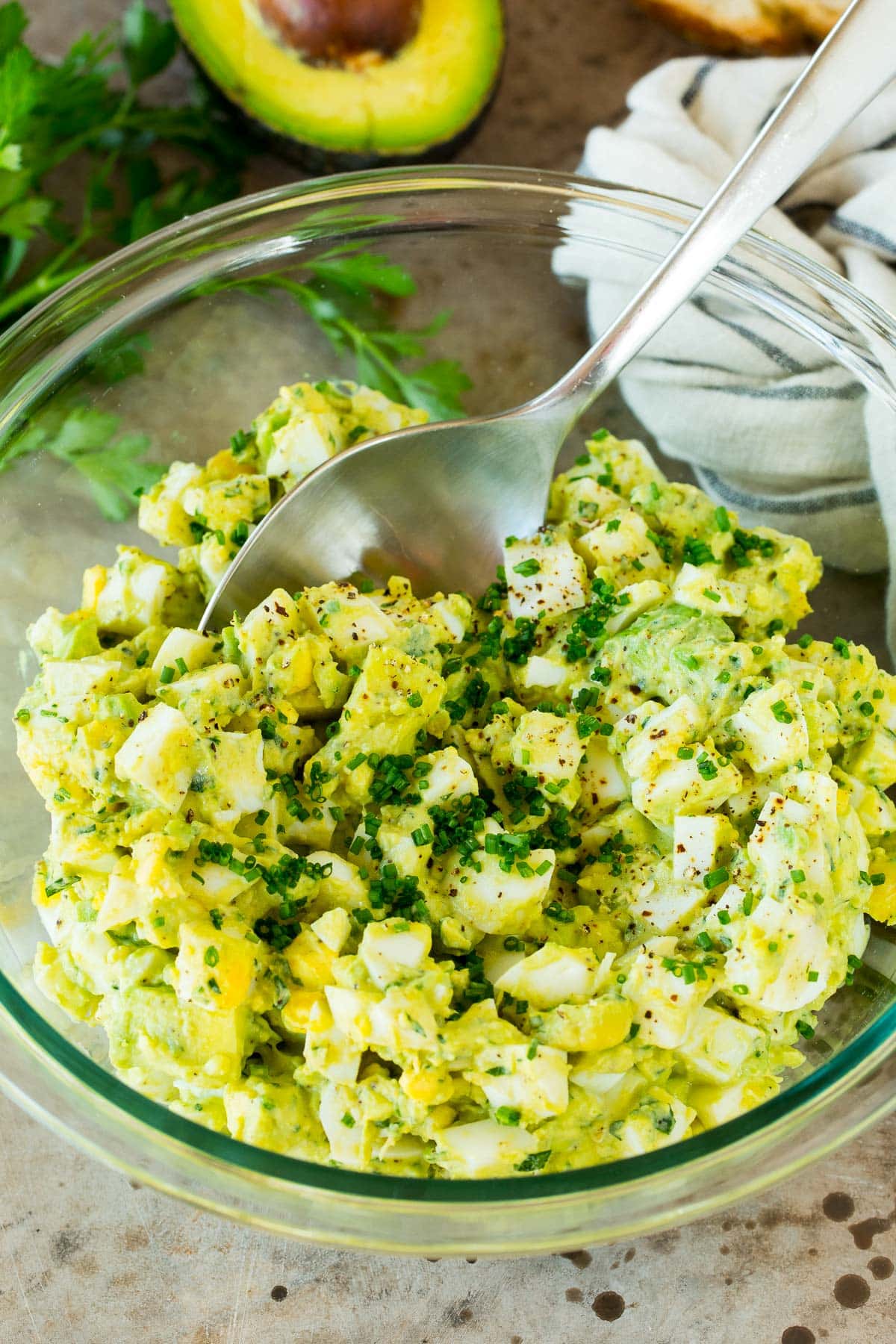 A serving spoon in a bowl of avocado egg salad.