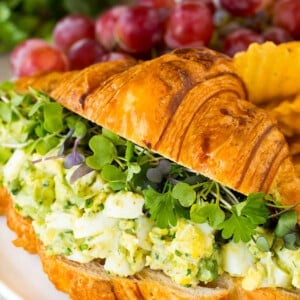 Avocado egg salad on a croissant with greens.