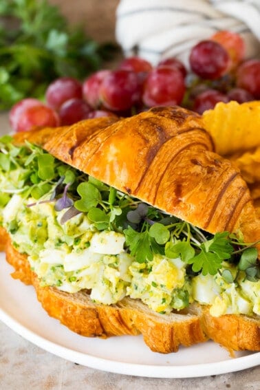 Avocado egg salad on a croissant with greens.