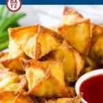 Several crab rangoon piled on a plate with a bowl of sweet and sour sauce.