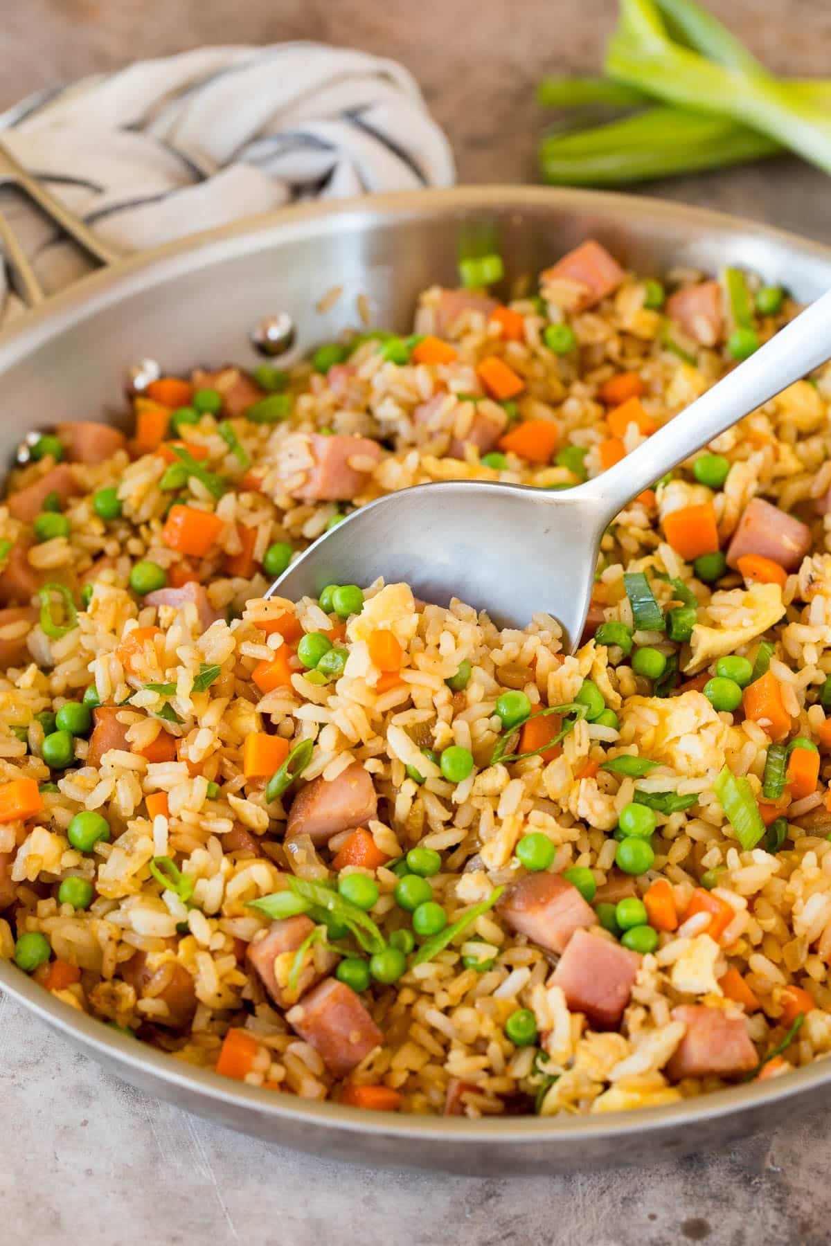 A pan of ham fried rice with a spoon in it.