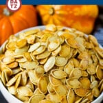 A bowl of roasted pumpkin seeds which are are coated in butter and seasonings, then baked until golden brown.