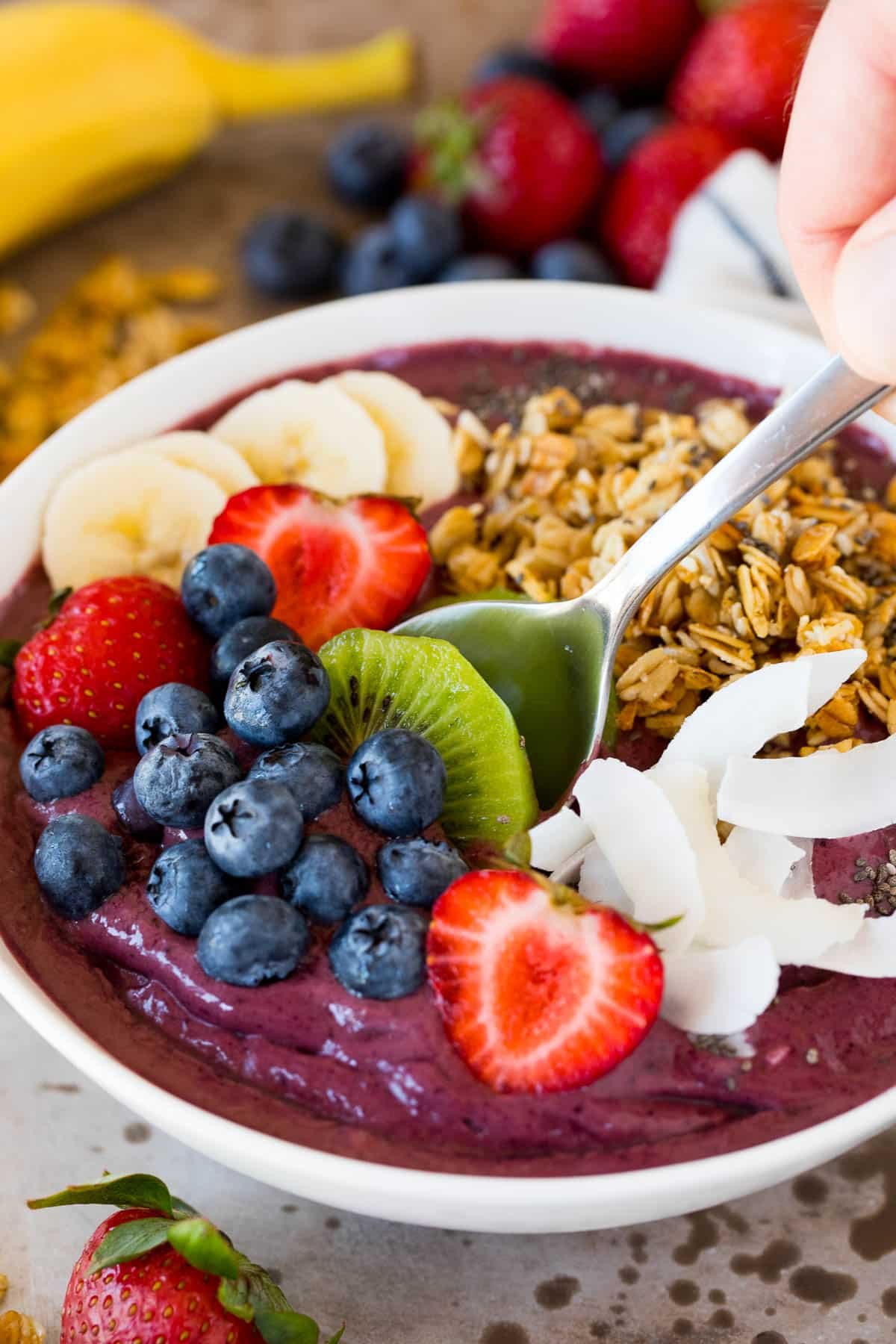 A spoon inside an acai bowl topped with berries.