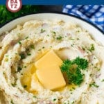 A pot of mashed red potatoes with butter and parsley on top.