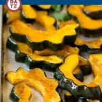 A sheet pan of roasted acorn squash slices garnished with parsley.