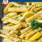 A sheet pan with roasted parsnips and garnished with parsley.