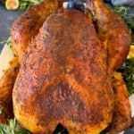 A Cajun turkey on a serving platter garnished with fruit and herbs.