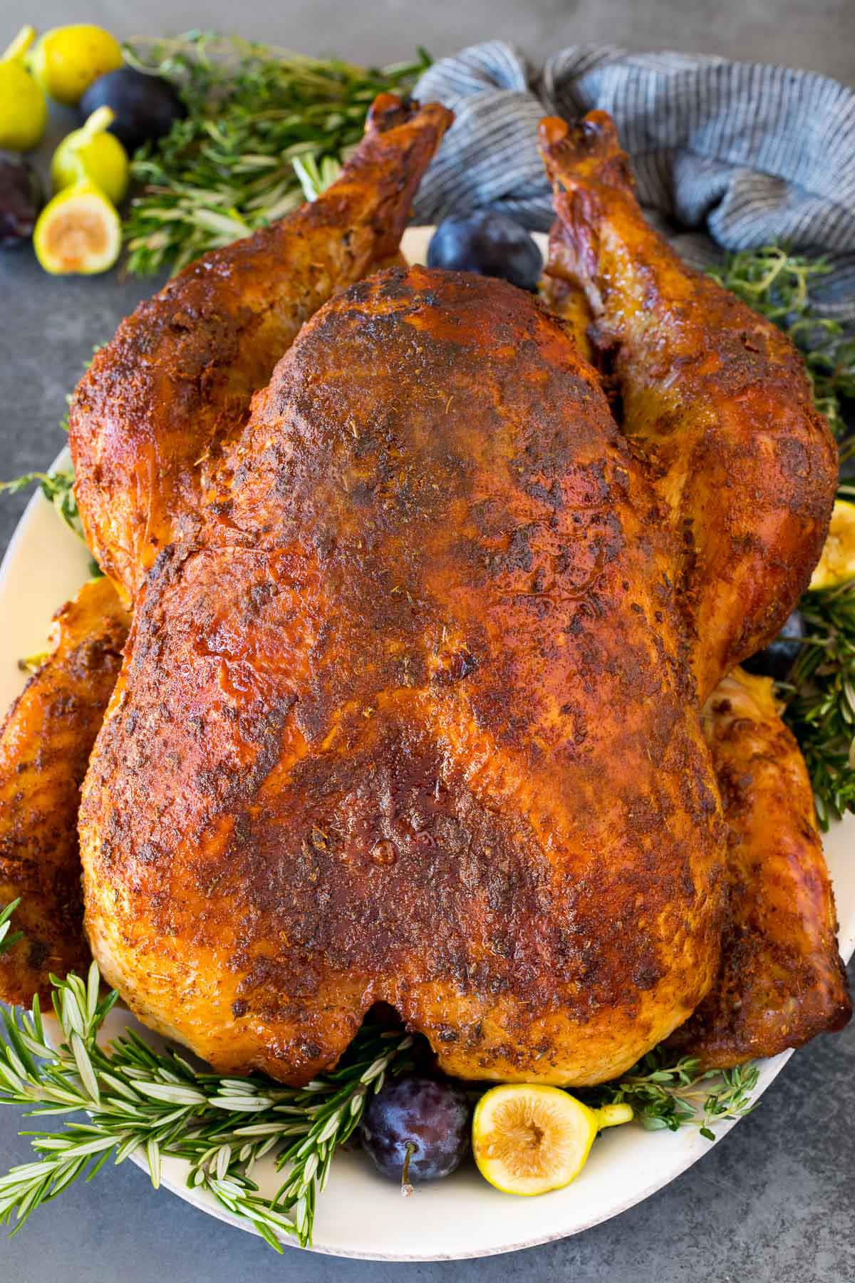 A Cajun turkey on a serving platter garnished with fruit and herbs.