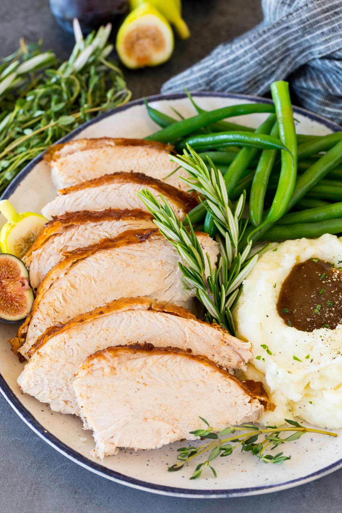 Sliced Cajun turkey on a plate with mashed potatoes and green beans.
