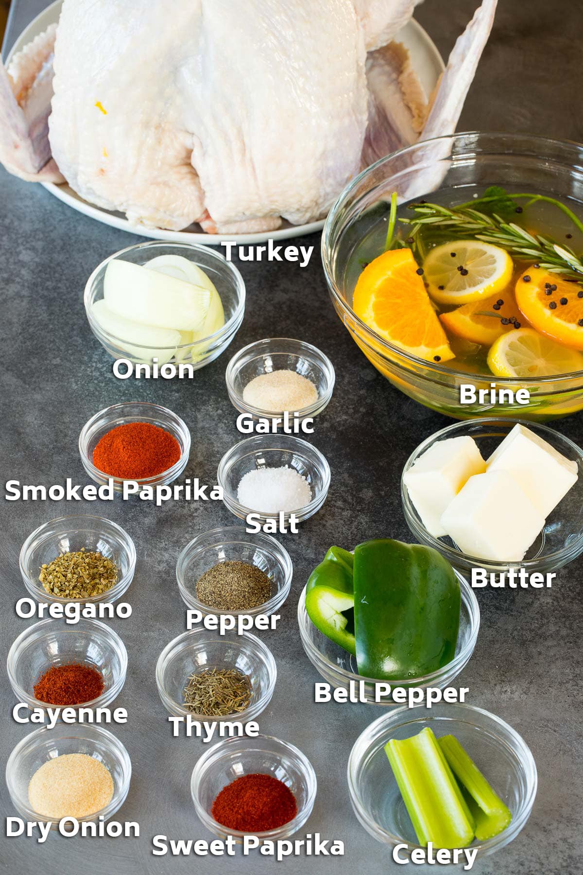 Ingredients including a turkey, brine, bowls of seasonings and vegetables.