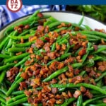 A pan of green beans with bacon on top.