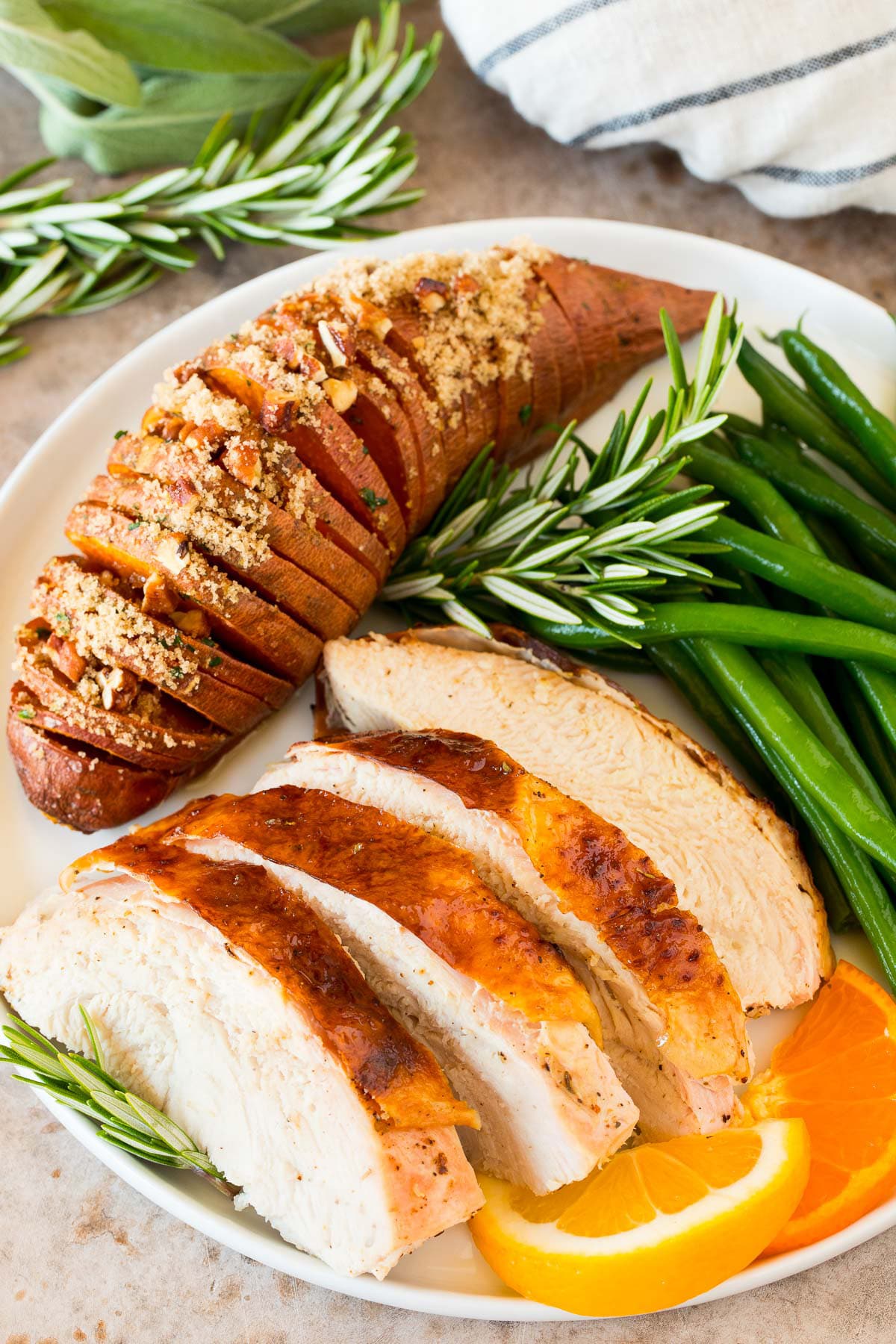 Sliced turkey on a plate with a sweet potato and green beans.
