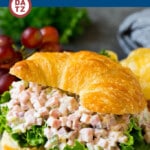 A croissant with creamy ham salad and lettuce on a a plate.